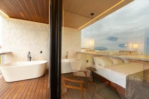 a bathroom with a tub and a large window at Nanii Hotel in São Miguel do Gostoso