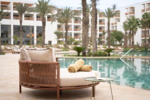 una silla de mimbre con almohadas y una mesa junto a la piscina en The View Agadir, en Agadir