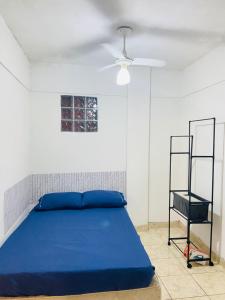 a bedroom with a blue bed and a fan at Maravilhosa Kitnet 10 min da praia in Vila Velha