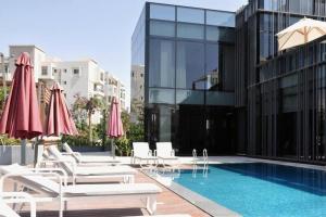 a pool with chairs and umbrellas next to a building at Access - luxurious apartment at cfc in Cairo