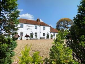 une grande maison blanche avec des arbres devant elle dans l'établissement Hambrook House Canterbury - NEW luxury guest house with ESPA Spa complex, à Canterbury