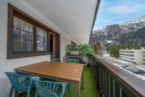 balcón con mesa de madera y sillas azules en Canin Mountain Lodge, en Sella Nevea