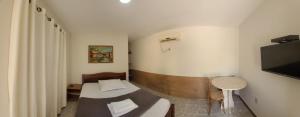 a small room with a bed and a small table at Pousada Aquarela in Guamaré