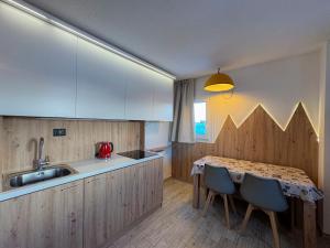 a kitchen with a table and chairs and a sink at Appartamento Biancaneve in Passo del Tonale