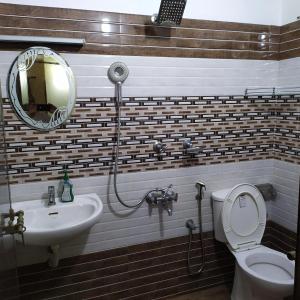 a bathroom with a sink and a toilet and a mirror at Sundance Beach Villa on Princess Street in Cochin