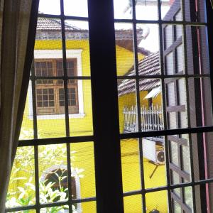 a view of a yellow house through a window at Sundance Beach Villa on Princess Street in Cochin