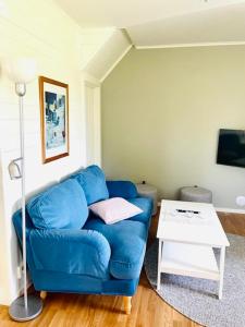 um sofá azul numa sala de estar com uma mesa em Bryggvingens Apartment 1 em Nösund