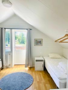 1 dormitorio con cama blanca y alfombra azul en Bryggvingens Apartment 1 en Nösund