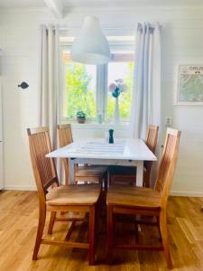 una mesa de comedor y sillas con una mesa blanca y una ventana en Bryggvingens Apartment 1 en Nösund