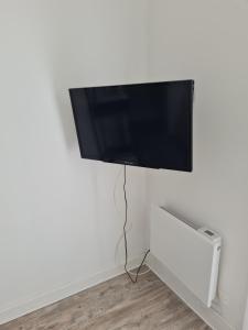 a flat screen tv hanging on a white wall at Le st jean familiale in Saint-Jean-de-la-Porte