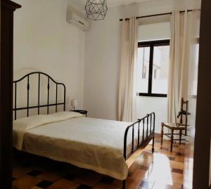 een slaapkamer met een bed, een stoel en een raam bij Il Patio in Sampieri