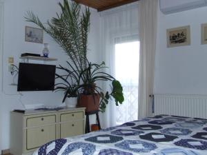 ein Schlafzimmer mit einem Bett und einer Kommode mit Pflanzen in der Unterkunft Czanek Apartman in Komárom