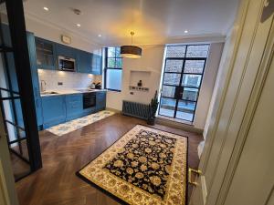 a kitchen with blue cabinets and a rug on the floor at Boutique Linden Gardens 1st floor and loft apartments in London +79 photos