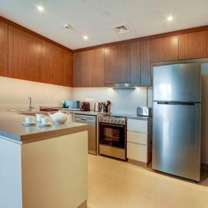 una cocina con electrodomésticos de acero inoxidable y armarios de madera en Beachwalk Luxury 2BR with Infinity Pool and Views, en Dubái