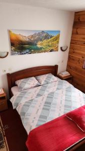 a bedroom with a bed with a painting on the wall at Olja Guest House in Žabljak