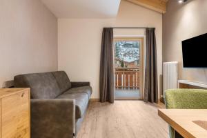 a living room with a couch and a television at Kamerloy Apartments G in Campitello di Fassa