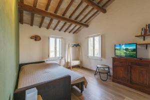 a bedroom with a bed and a flat screen tv at Casale Grifondoro in Pergola