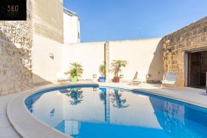 a swimming pool in front of a building at A stunning, townhouse with magnificent pool area by 360 Estates in Żebbuġ