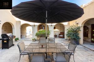 a table and chairs with an umbrella on a patio at A stunning, townhouse with magnificent pool area by 360 Estates in Żebbuġ