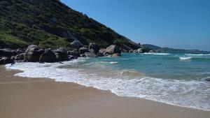 una playa de arena con rocas y el océano en Pousada ZAUA GUEST HOUSE, en Florianópolis