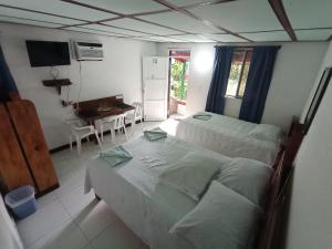 a bedroom with two beds and a table and a desk at Hospedaje Turistico Angula Place in San Andrés