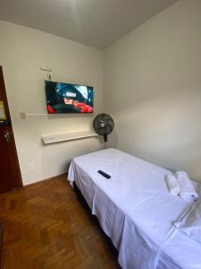 a bedroom with a white bed and a flat screen tv at Pousada automática sem recepção 1 in Uberlândia