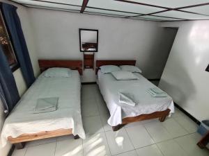 two beds in a room with a tv on the wall at Hospedaje Turistico Angula Place in San Andrés