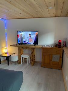 a living room with a television on a wooden desk at Chambre privée in Aime-La Plagne