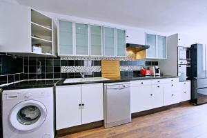 una cucina con armadietti bianchi e lavatrice di Spacious nest for 8 people with balcony a Saint-Denis