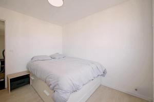 una camera bianca con un letto su una parete bianca di Spacious nest for 8 people with balcony a Saint-Denis