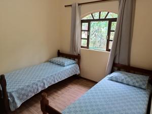 two beds in a room with a window at Pousada Serra Verde Ecolodges in Morretes