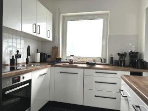 a kitchen with white cabinets and a window at Mid - Century in Schloß Holte-Stukenbrock