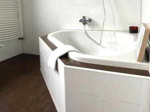 a white bathroom with a tub with a towel on it at Mid - Century in Schloß Holte-Stukenbrock