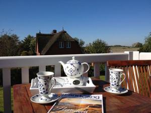 a table with two tea pots and cups on a balcony at FW Beisel in Garding