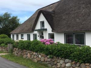 a white house with a thatched roof and pink flowers at EG Inge in Katharinenheerd