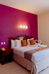 1 dormitorio con 2 camas y pared púrpura en Hotel Plaza Campeche, en Campeche