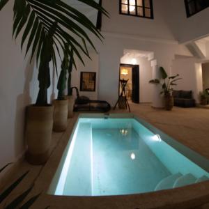 una piscina en una sala de estar con una palmera en Riad 27 en Marrakech