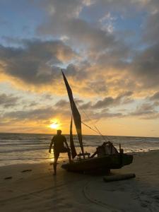 POUSADA CHALÉ PARAÍSO - Icapui في إيكابوي: رجل يمشي على الشاطئ بقارب شراعي