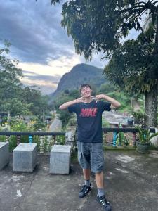 a young man standing on a ledge with his hands on his head at Rock View Hostel Ella in Ella