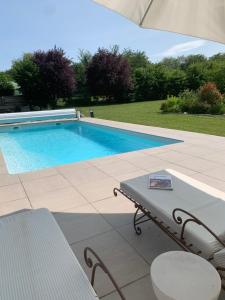 uma piscina com mesa e cadeiras ao lado em Chambres d hôtes La clé des arches em Sainte-Florine