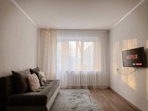 a living room with a couch and a window at Квартира в тихом районе правого берега Астаны in Astana