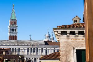 um edifício alto com uma torre de relógio e um edifício com um relógio em Hotel Palazzina Sardi em Veneza