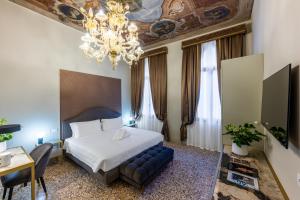 Habitación de hotel con cama y lámpara de araña. en Hotel Palazzina Sardi, en Venecia