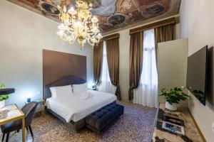 Habitación de hotel con cama y lámpara de araña. en Palazzina Sardi, en Venecia