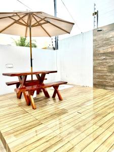 uma mesa de piquenique com um guarda-chuva num piso de madeira em Carapibus casa de praia 02 em Conde