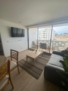 a living room with a couch and a large window at Departamentos Bahia Suites in Bahia Inglesa