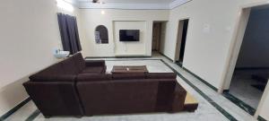 a living room with a brown couch and a tv at MSD villa in Puducherry