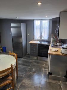 eine Küche mit einem Kühlschrank aus Edelstahl und einem Tisch in der Unterkunft Appartement avec terrain in Pézenas