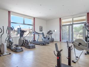 une salle de sport avec plusieurs tapis de course et machines elliptiques dans l'établissement Vacanceole - Residence les Demeures du Ventoux, à Aubignan