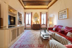 a living room with a red couch and a tv at Fortuny 3967 Luxury suites wine in Venice